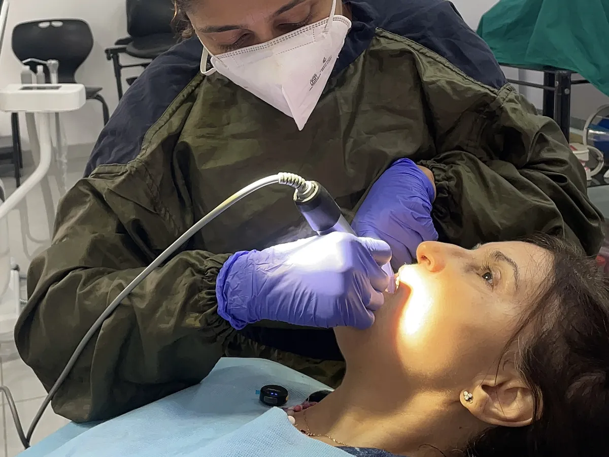A dentist examining a patient's teeth under the chair light at Prudent Dental Clinic, Viman Nagar, Pune