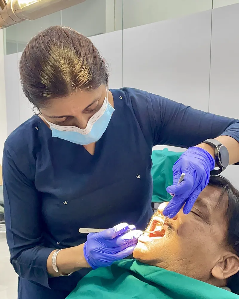 A dentist at Prudent Dental Clinic examining a patient with a mouth mirror